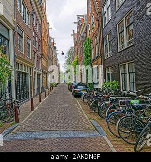 Amsterdam biciclette parcheggiate nella vecchia strada di ciottoli Foto Stock