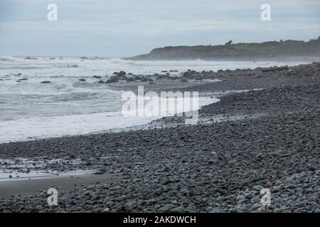 Forti onde si infrangono sulla spiaggia rocciosa di Dulan Beach, nel sud di Taiwan, dopo un ciclone passò da, lavaggio a terra di grandi pezzi di driftwood Foto Stock