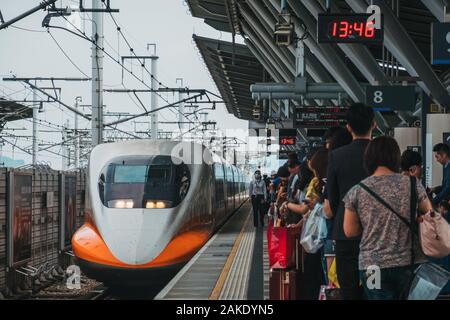 I passeggeri in attesa su piattaforma come Taiwan high speed rail bullet train arriva a Tainan HSR stazione, Taiwan Foto Stock