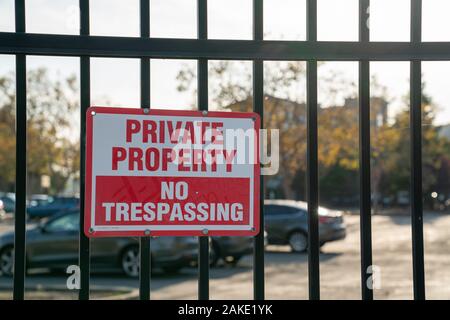 La proprietà privata senza sconfinamenti di cartello sul cancello nero nella parte anteriore del parcheggio Foto Stock