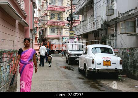 Kolkata, India - 5 Dicembre 2019 : donna indiana in sari o saree abito tradizionale a piedi a lavorare con padre tenendo la mano del bambino per andare a scuola su Foto Stock