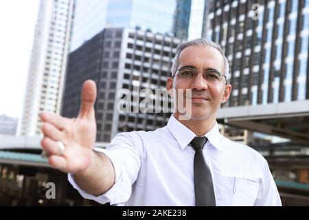 Fiducioso imprenditore di successo professionale handshake rendendo di fronte all edificio per uffici nel centro affari della città dopo dando opportunità di ne Foto Stock