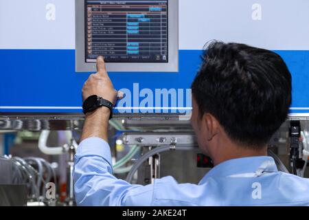 Ingegnere in fabbrica il controllo e premendo importante tecnologia pulsante sul pannello di controllo di una macchina automatica per la produzione. Il fuoco selettivo. Foto Stock