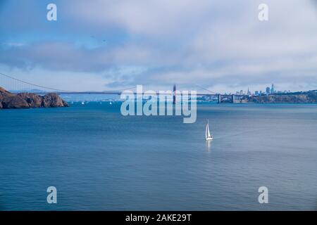 Yacht a vela in parte anteriore del ponte Golden Gate in acque aperte con San Francisco skyline della città Foto Stock
