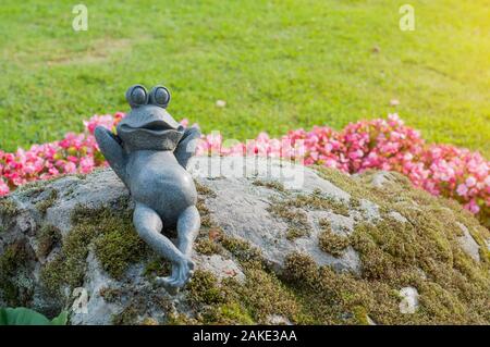 Rana decorativa in giardino.ceramica rana verde figurina, rana seduta sulle pietre Foto Stock
