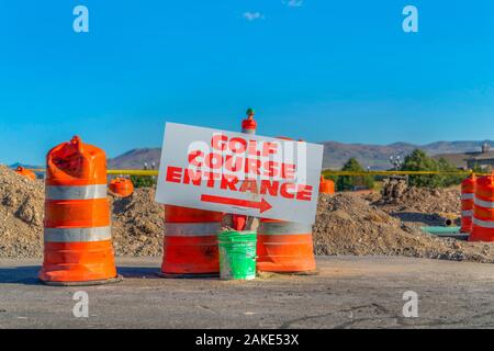 Strada in costruzione con campo da golf entrata segno e barili di traffico Foto Stock