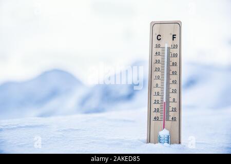 Termometro sulle montagne nella neve mostra temperature sotto zero. Basse temperature in gradi Celsius e Fahrenheit Foto Stock