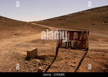 Una via per il sud nei pressi di sidi ifni, Marocco. La pista conduce all'orizzonte. Un segno della strada che conduce a fort bou sceriffo Foto Stock