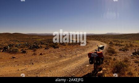 Una pista rettilinea per il sud nei pressi di sidi ifni, Marocco. la strada che conduce all'orizzonte. Un viaggio in bicicletta la parte anteriore della foto Foto Stock