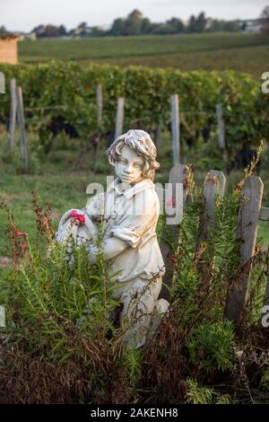 Saint Emilion, Francia - 12 Settembre 2018: Statua di un ragazzo tenendo un cesto con uva sullo sfondo dei vigneti in Saint Emilion regione. F Foto Stock