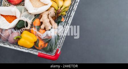 Frutta e verdura, grani riutilizzabili in tessuto tessile borse nel carrello. Vista superiore piatta o laici. Copia dello spazio. Carrello con il cibo vicino, studio shot. I rifiuti alimentari, rifiuti zero il concetto di shopping. Banner Foto Stock