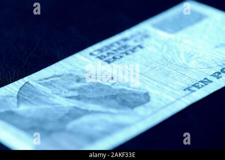 Dieci sterline egiziane bill su uno sfondo scuro di close-up. Il denaro di sfondo di colore blu tonica Foto Stock