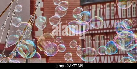 Bolle di sapone con deliberatamente sfocato a struttura mista in legno e muratura edifici in background Foto Stock