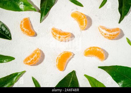 Telaio con foglie verdi e mandarino agrumi sfondo. Fette di mandarino, Mandarine clementine, su sfondo bianco. Vista superiore Foto Stock