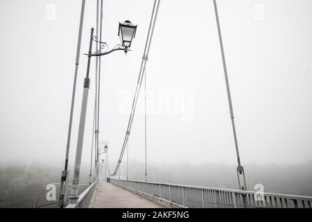 Ponte con nebbia in toni di grigio. La malinconia brumoso paesaggio con ponte e lampade. Stagione, meteo, umore concept Foto Stock