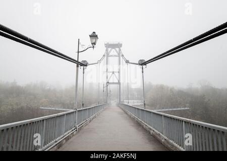 Ponte con nebbia in toni di grigio. La malinconia brumoso paesaggio con ponte e lampade. Stagione, meteo, umore concept Foto Stock