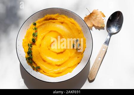 Autunno purea di zucca in una terrina. Autunnale di crema di zucca minestra con timo bianco sul tavolo. Autunno gustoso cibo vegetariano. Vista superiore Foto Stock