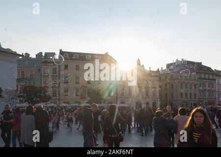 La gente guarda un uomo che crea bolle giganti nel Rynek Glowny (Piazza del mercato principale) nel centro di Cracovia (Cracovia), Polonia Foto Stock