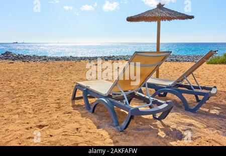 Spiaggia di sabbia fine attrezzata con ombrelloni e sedie a sdraio in riva al mare sulla soleggiata giornata estiva Foto Stock