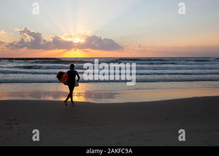 Silhouette di surfisti sulla spiaggia del mar Mediterraneo. Fotografato a Tel Aviv al tramonto Foto Stock