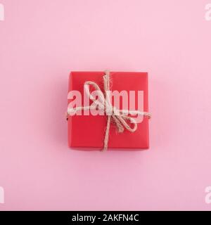 Confezione regalo rossa su sfondo rosa. Lay piatto. Vista superiore Foto Stock