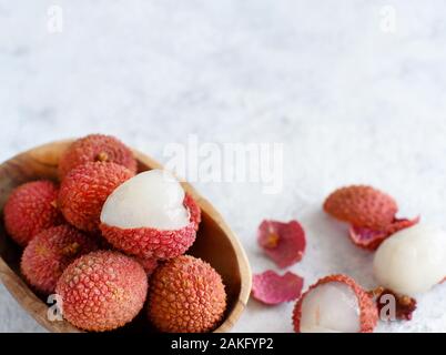 Litchi freschi frutti in un recipiente in un tavolo bianco close up Foto Stock