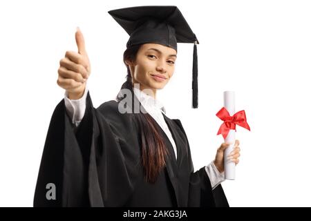 Studentessa in un abito di laurea in possesso di un diploma e mostrando pollice in alto isolato su sfondo bianco Foto Stock