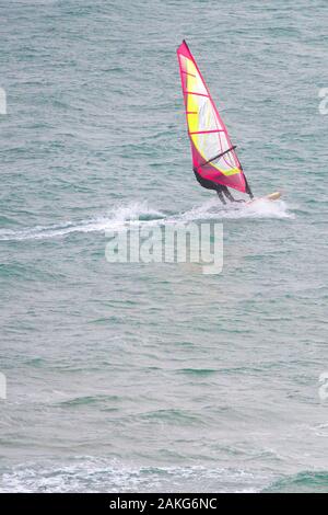 Una scrematura windsurfista in velocità sul mare a Crantock a Newquay in Cornovaglia. Foto Stock