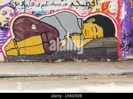 L'Egitto, al Cairo, graffiti della rivoluzione egiziana su Mohamed Mahmoud Street. Un bambino di strada a dormire. Foto Stock