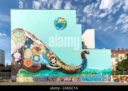 Ampio angolo di vista di un enorme graffiti sul lato di un alto edificio che raffigura un elefante colorato contro uno sfondo blu chiaro Foto Stock