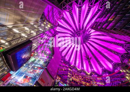 Ampia vista notturna della sala principale del Sony Centre di Potsdamer Platz, con il tetto a forma di fiore illuminato da luci viola Foto Stock