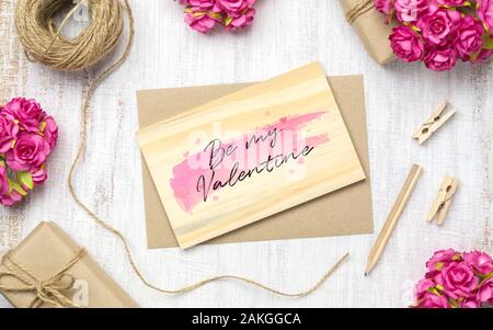 Mockup vuoto scheda di legno e avvolgere su grunge di legno bianco con carta kraft rose e fatto a mano artigianale scatola regalo per il giorno di San Valentino. Mock up per eleganti Foto Stock