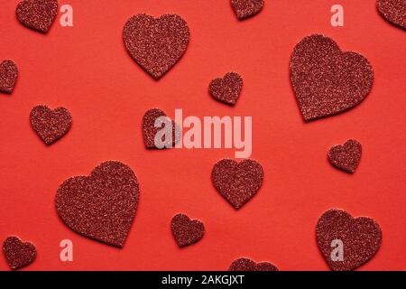 Amore a tema sfondo rosso a forma di cuore glitter cuori in varie dimensioni - il giorno di San Valentino il matrimonio o un anniversario concetto Foto Stock