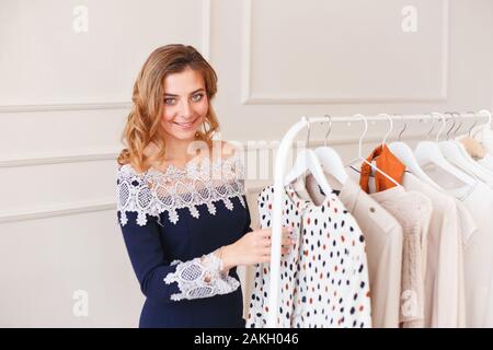 Giovane donna scegliendo i vestiti su una rastrelliera per il partito Foto Stock