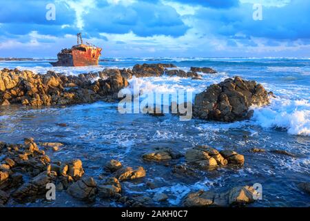 Sud Africa, Western Cape, relitto affondato al tramonto sulla costa rocciosa di Cape Aghulas dove l'Oceano Indiano incontra l'Oceano Atlantico Foto Stock