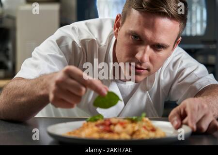 Lo Chef maschio piastra di farcitura di prodotti alimentari in cucina professionale Foto Stock