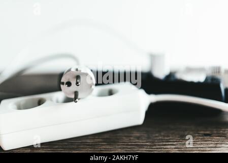 Close-up di striscia di alimentazione con spina scollegata sul tavolo di legno Foto Stock