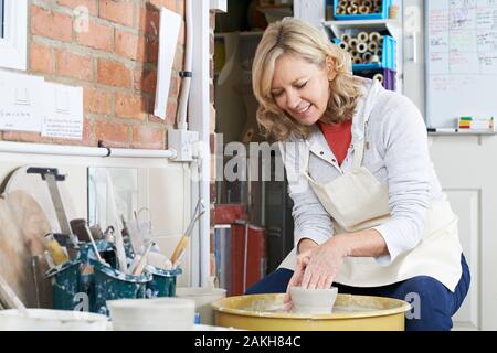 Donna matura lavorando a Potters ruota in Studio Foto Stock
