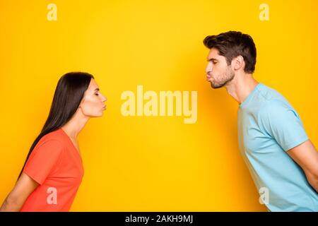 Foto del profilo di divertenti carino due persone guy lady gli occhi chiusi in piedi di fronte alla cieca baci dating indossare casual blue t-shirt arancione giallo isolato Foto Stock