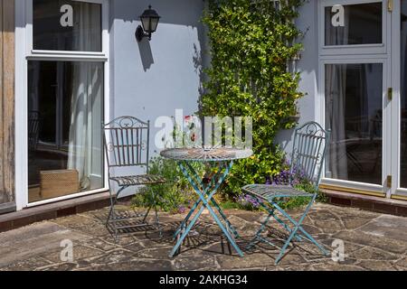 Mobili da giardino in metallo sul patio in pietra nel giardino estivo inglese Foto Stock