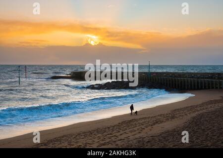 West Bay, Dorset, Regno Unito. 9 gennaio 2020. Regno Unito Meteo. Un dog walker sulla spiaggia a est di West Bay nel Dorset poco prima del tramonto. Credito Foto: Graham Hunt/Alamy Live News Foto Stock