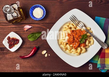 Pesto rosso pasta con gli ingredienti su di un legno scuro dello sfondo. Foto Stock