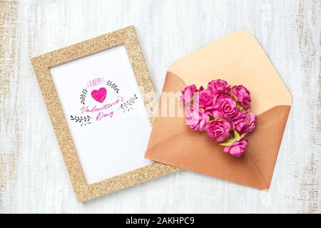 Mockup golden picture frame per il giorno di San Valentino del concetto. Flat Top laici vista di mock up photo frame con craft rose fiori in busta su grunge w bianco Foto Stock