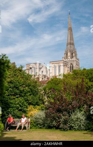 Due donne relax su una panchina nel Palazzo del Vescovo giardini con la Cattedrale di Chichester, West Sussex, come sfondo. Foto Stock