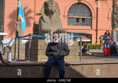 Il Cairo, Egitto - 22 Gennaio 2013: un ragazzo seduto vicino alla sfinge egizia del Museo Nazionale al Cairo il 22 gennaio 2013. Foto Stock