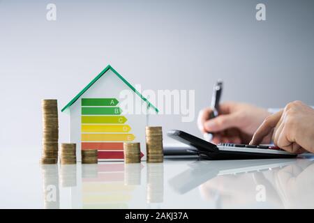 L'uomo calcolo fattura con efficienza energetica grafico e casa Foto Stock