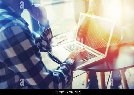 Business man funziona con computer portatile su un tavolo in un ufficio moderno vicino la pianificazione della finestra il suo futuro. Doppio effetto di esposizione con un grattacielo Foto Stock