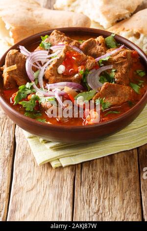 In stile Georgiano piccante stufato di manzo Chashushuli Ostri close-up in una ciotola sul piano verticale. Foto Stock