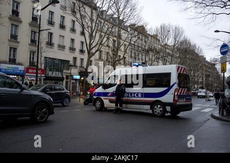 Furgone della polizia francese parcheggiato in strada, chiudendo la strada al traffico, come ufficiale di polizia sta vicino, in previsione delle proteste a causa delle riforme pensionistiche proposte dal governo, causando interruzioni di viaggio, sciopero di Parigi (la grève), boulevard Barbès, 75018, Parigi, Francia, 9th gennaio 2020 Foto Stock