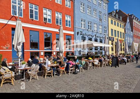 Gli storici ristoranti sul lungomare di Nyhavn, Copenhagen, attraggono centinaia di turisti e Copenaghen per un pranzo all'aperto in una soleggiata giornata primaverile. Foto Stock